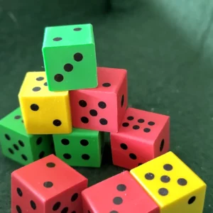 Dé en gomme vert, rouge, jaune avec points noirs.